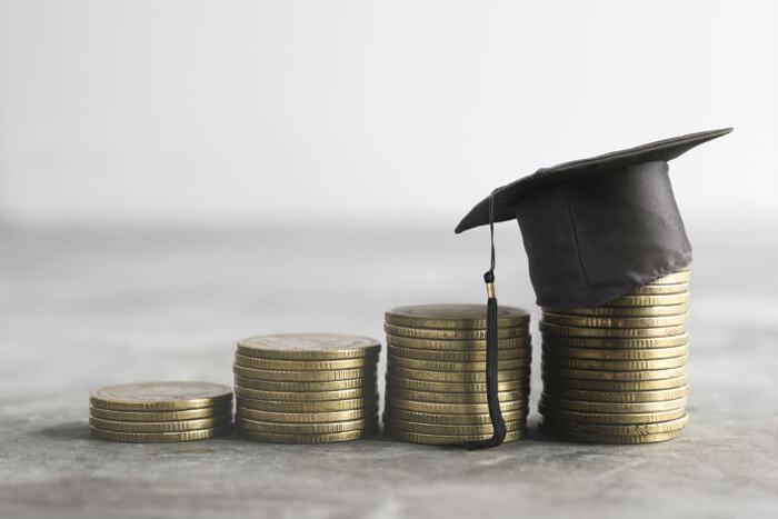 Geld für Bildung: Absolventenkappe auf Münzstapel