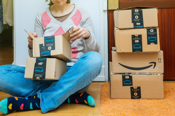Frau sitzt mit Amazon Paketen aufm Boden