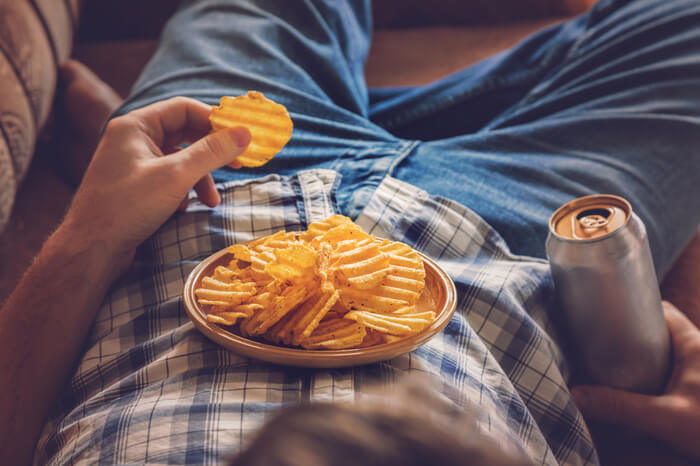 Binge Watchning: Mann liegt im Sessel mit Chips
