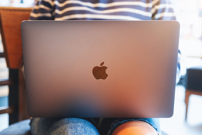 Frau mit Apple-Laptop auf dem Schoß
