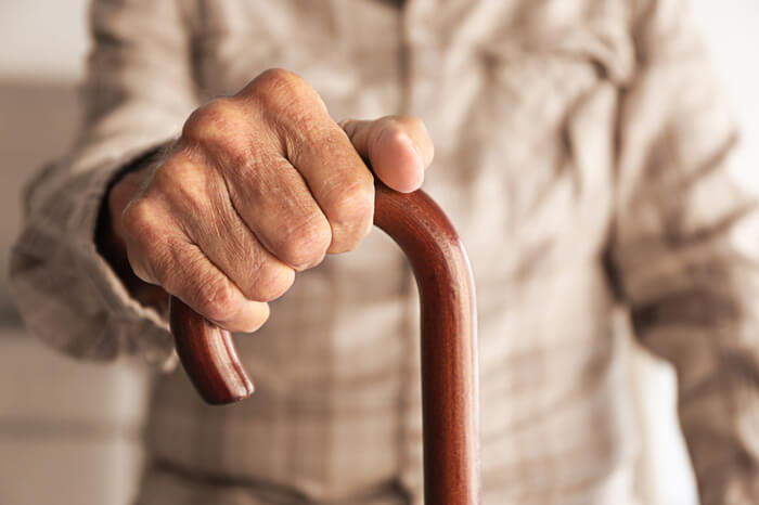 Älterer Mensch: Hände auf Gehstock