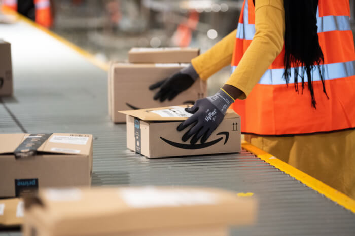 Amazon-Mitarbeiterin am Förderband mit Paketen