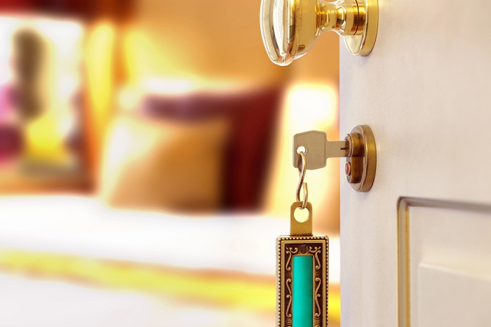 Halb geöffnete Hotelzimmertür mit goldverziertem Schüssel