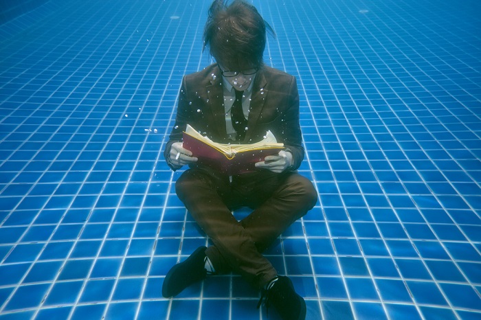 Mann liest Buch unter Wasser