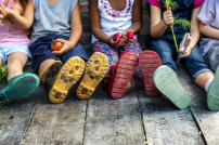 Vorschule für ärmere Kinder: Kids sitzen auf dem Boden und halten Gemüse in den Händen